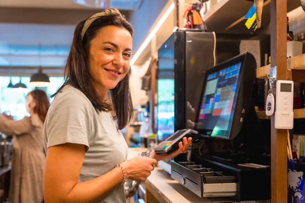 Funcionária de restaurante utilizando PDV para restaurantes com máquina de cartão e sistema digital integrado.